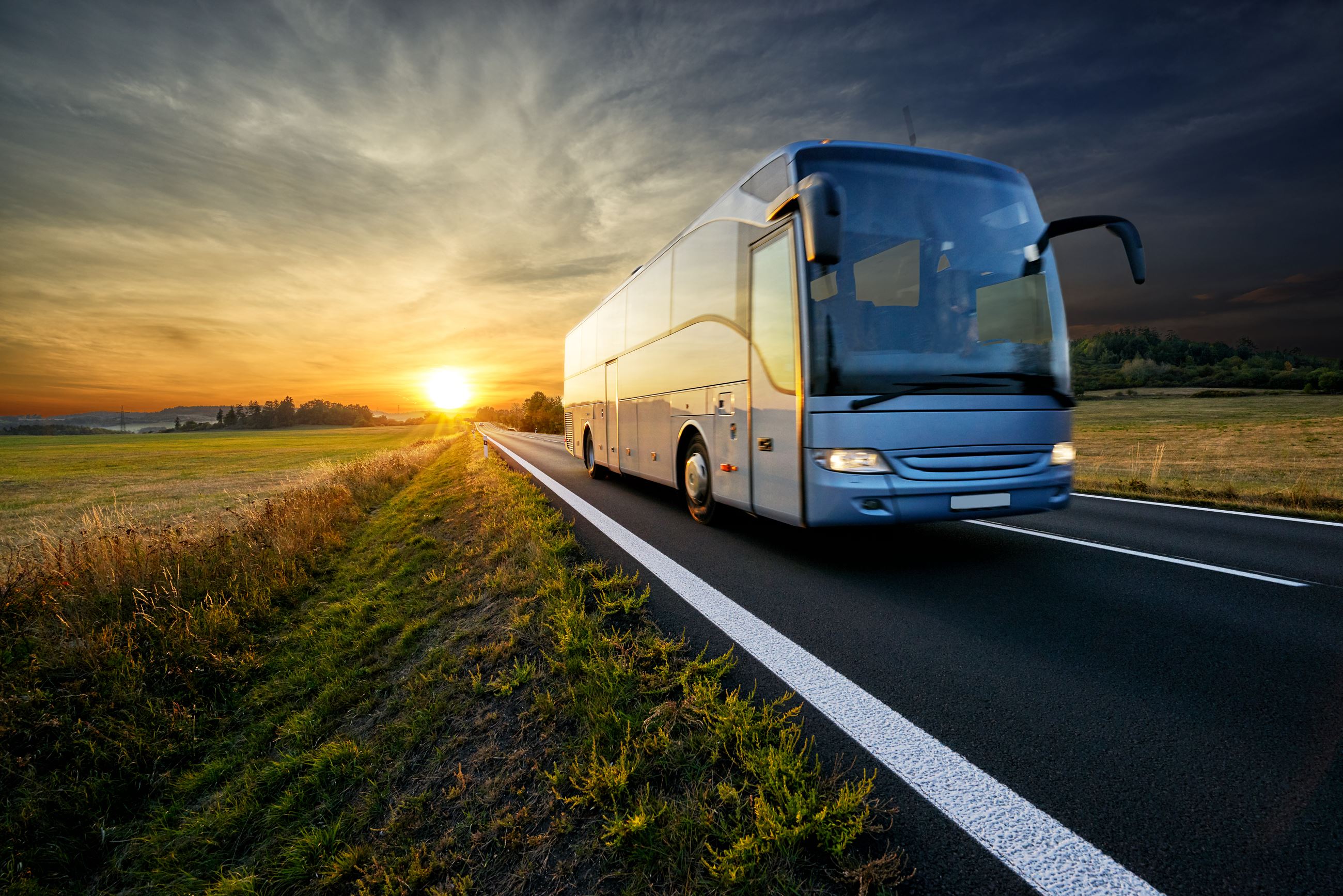 Image of a bus driving down the road at sunset