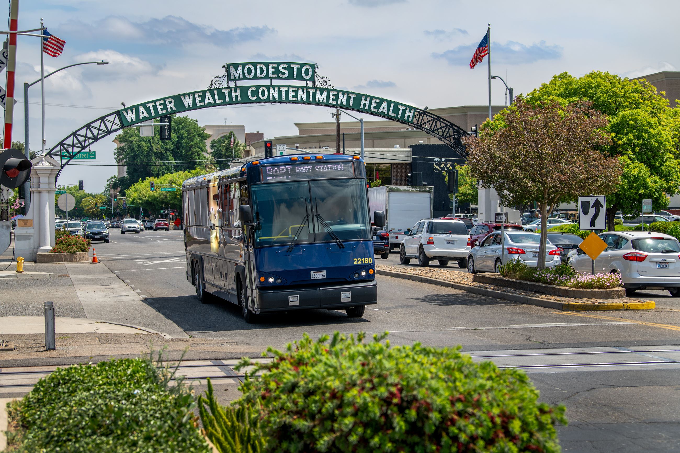 Image of a BART Commuter bus driving under the Modesto Arch